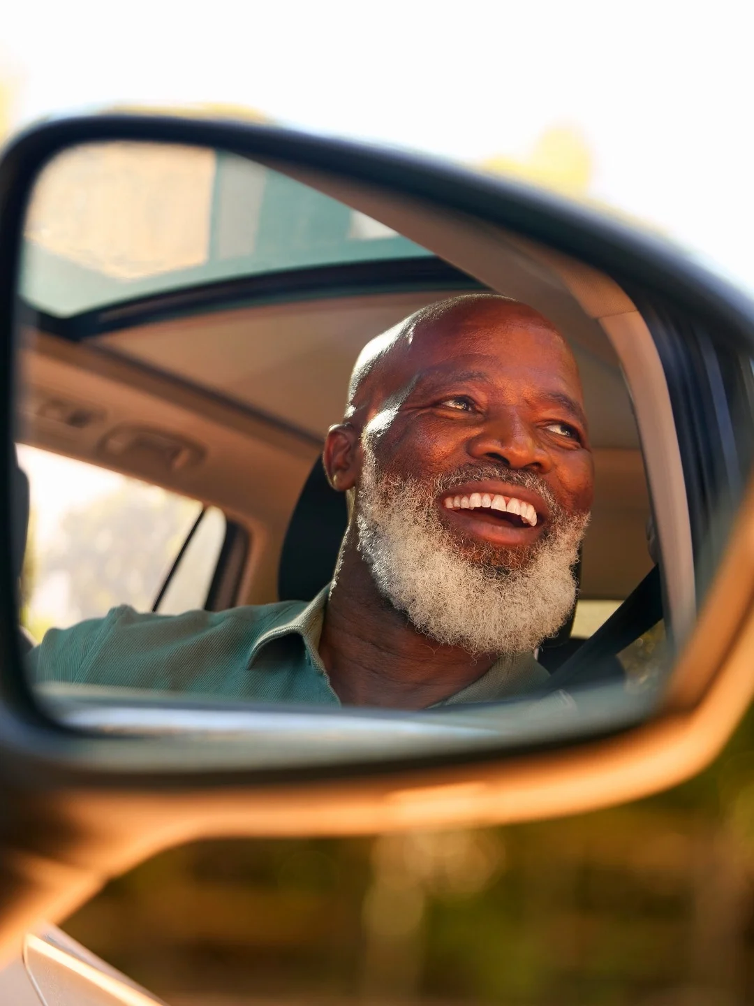 Smiling driver seen in his car’s side mirror