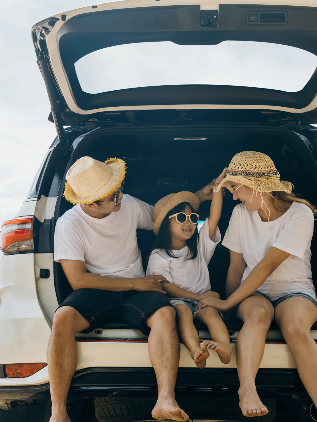 Family sitting together in the open trunk of their car
