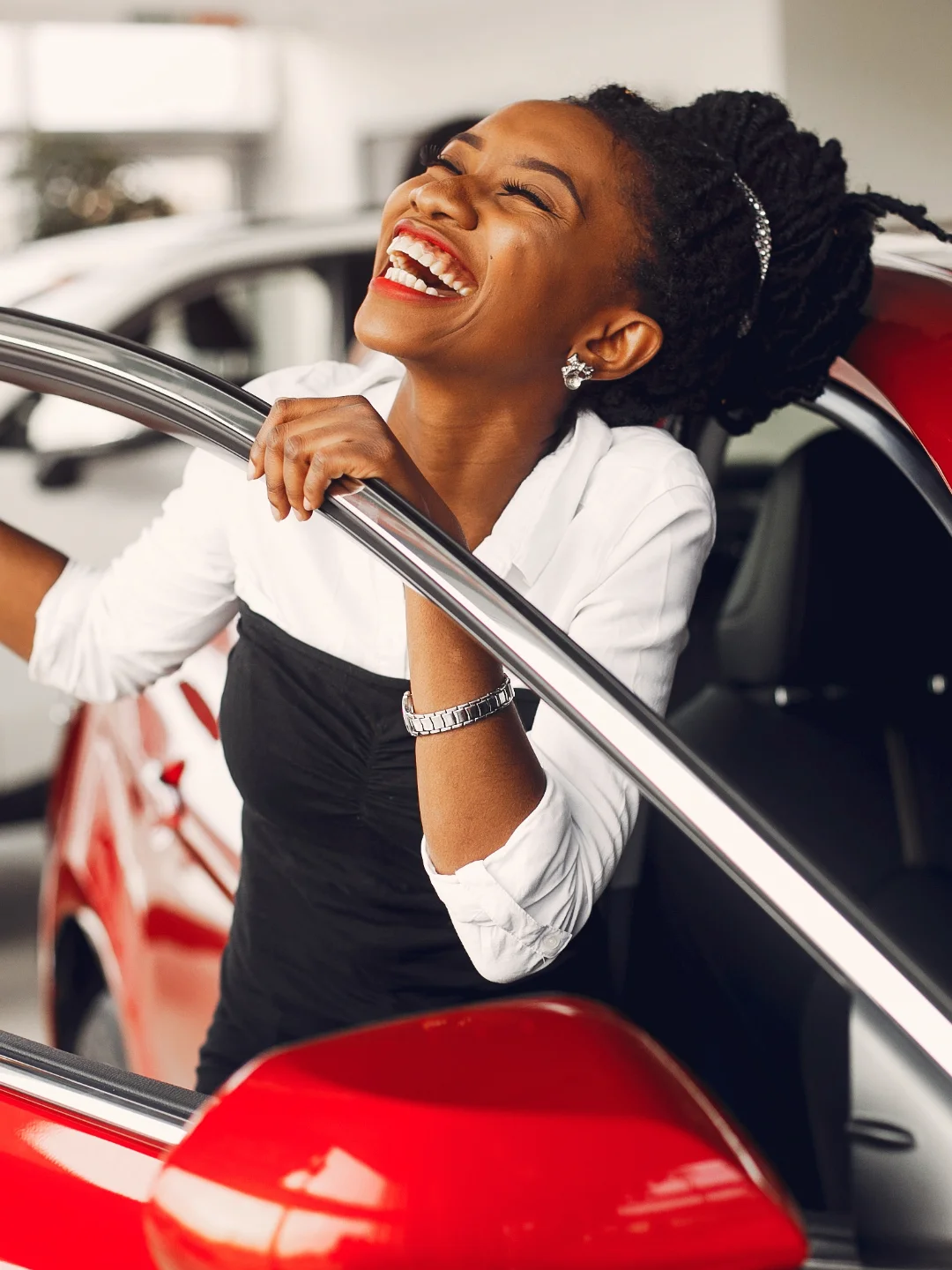 Woman smiling as she opens the door of her red car
