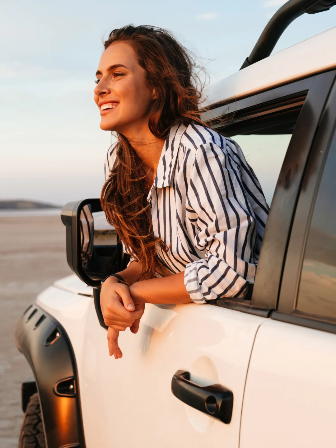 Woman leaning out of her car window by the beach