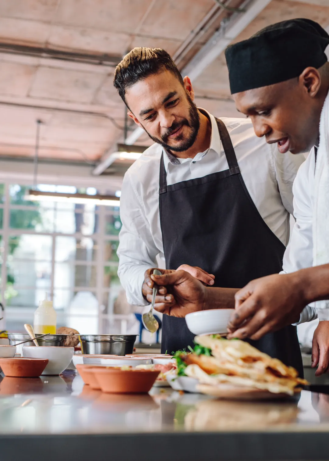 Restaurant owner and chef preparing dishes together in the kitchen